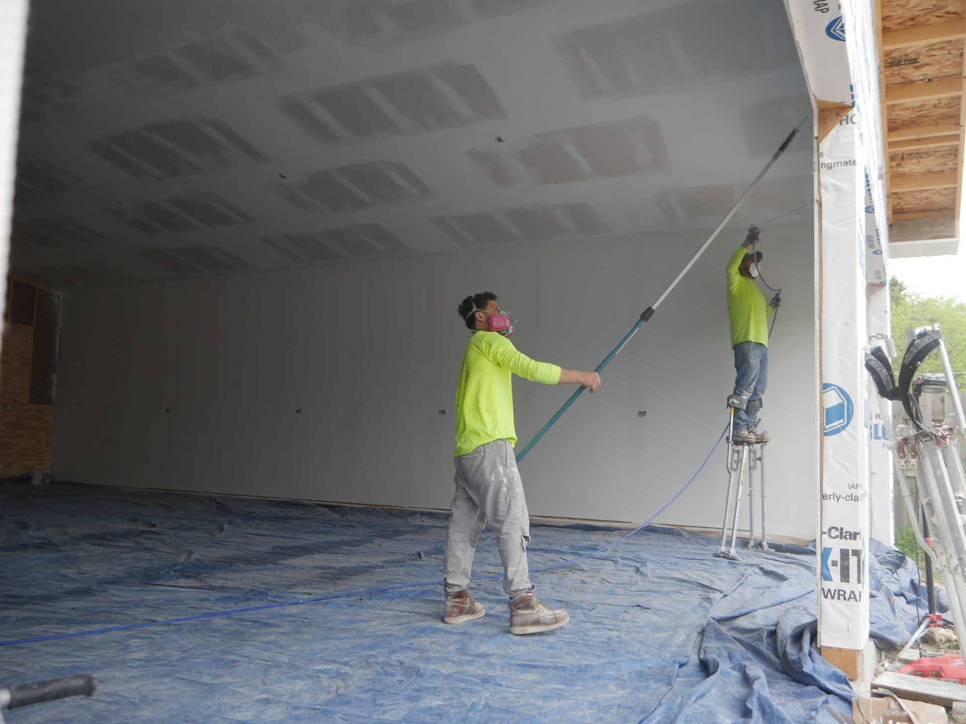 Great Lakes Drywall finisher skim-coating a Level 5 wall on stilts inside an Illinois home